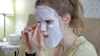 在家中的厨房里，一个正在做面膜面罩面膜的年轻女人